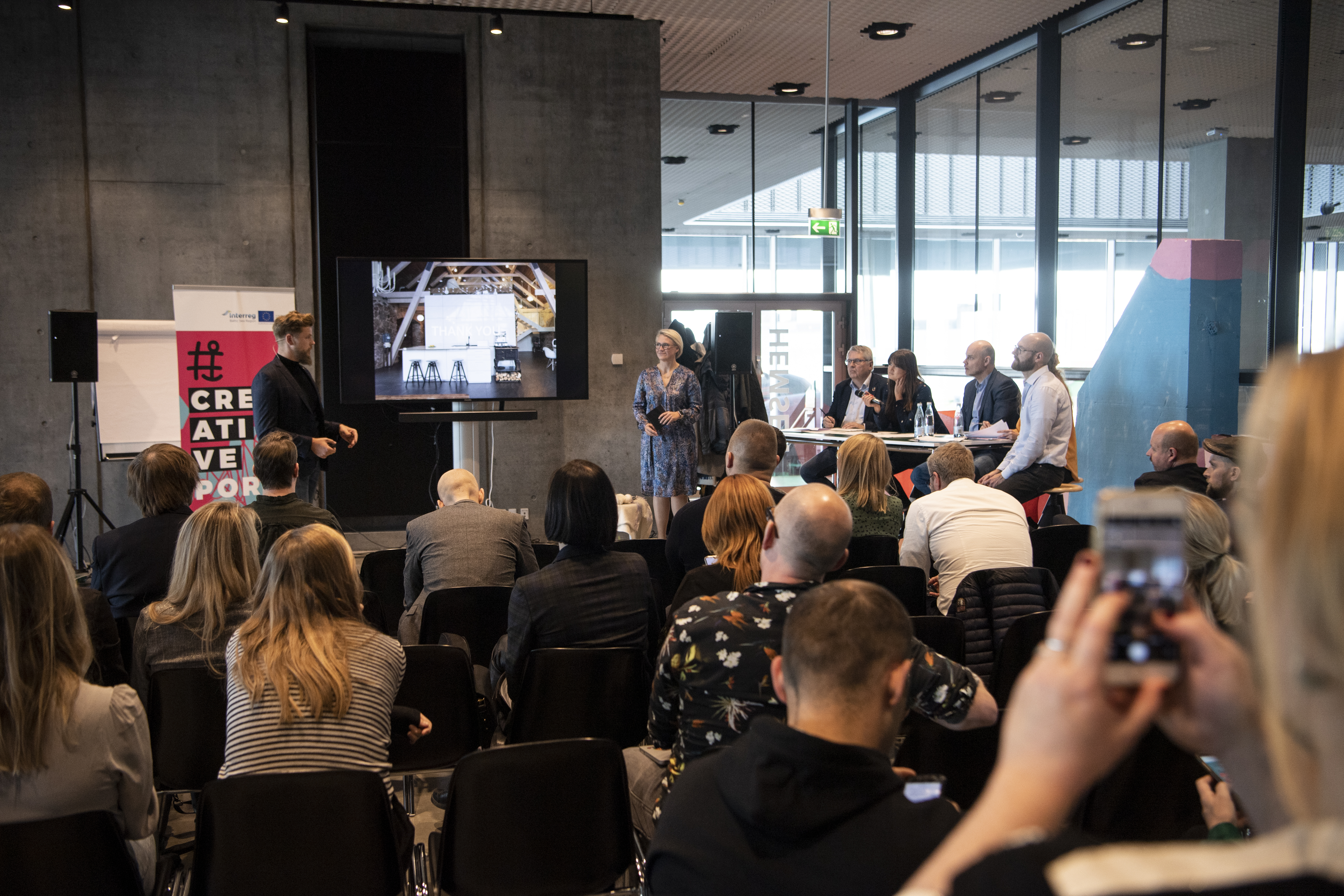 photo of the backs of people seated in an audiece. focus on the presenter.